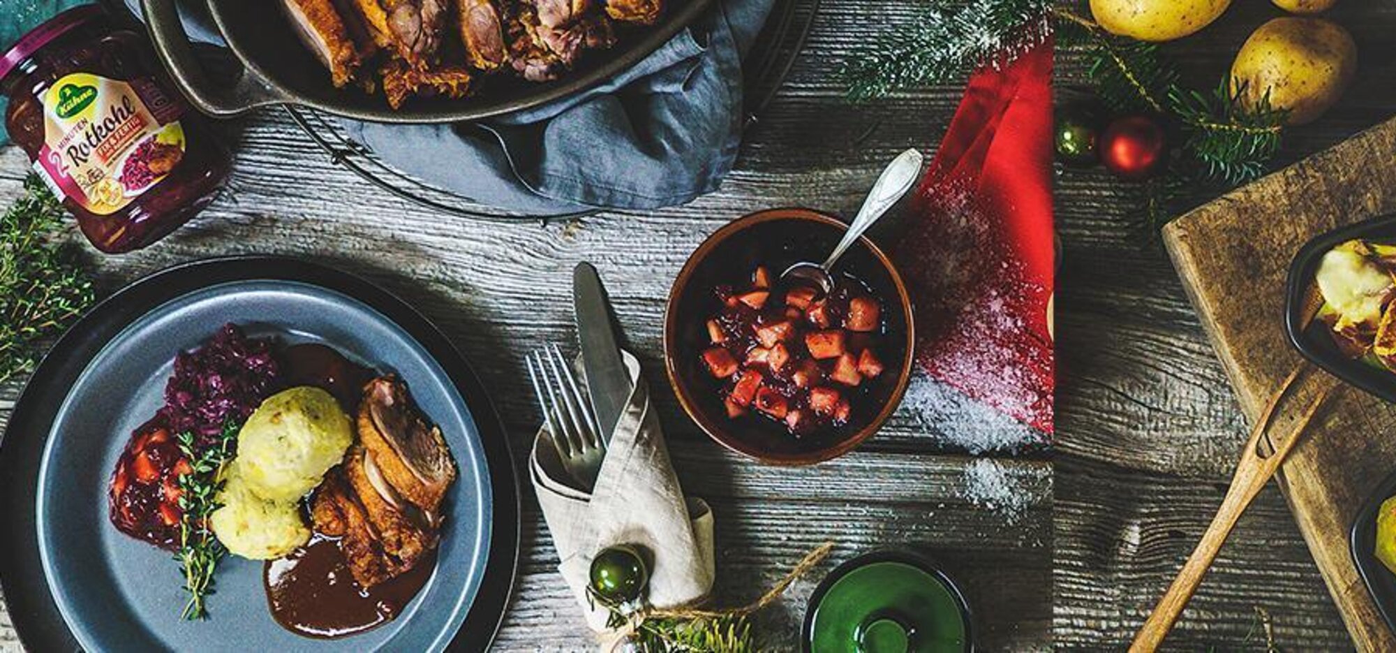 Ein Schüssel mit Preiselbeeren mit Apfelstücken und eine Raclette-Pfanne auf einem rustikalen Tisch von oben