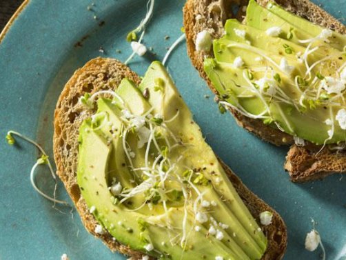 Zwei Scheiben Brot, belegt mit Avocado und Kresse von oben