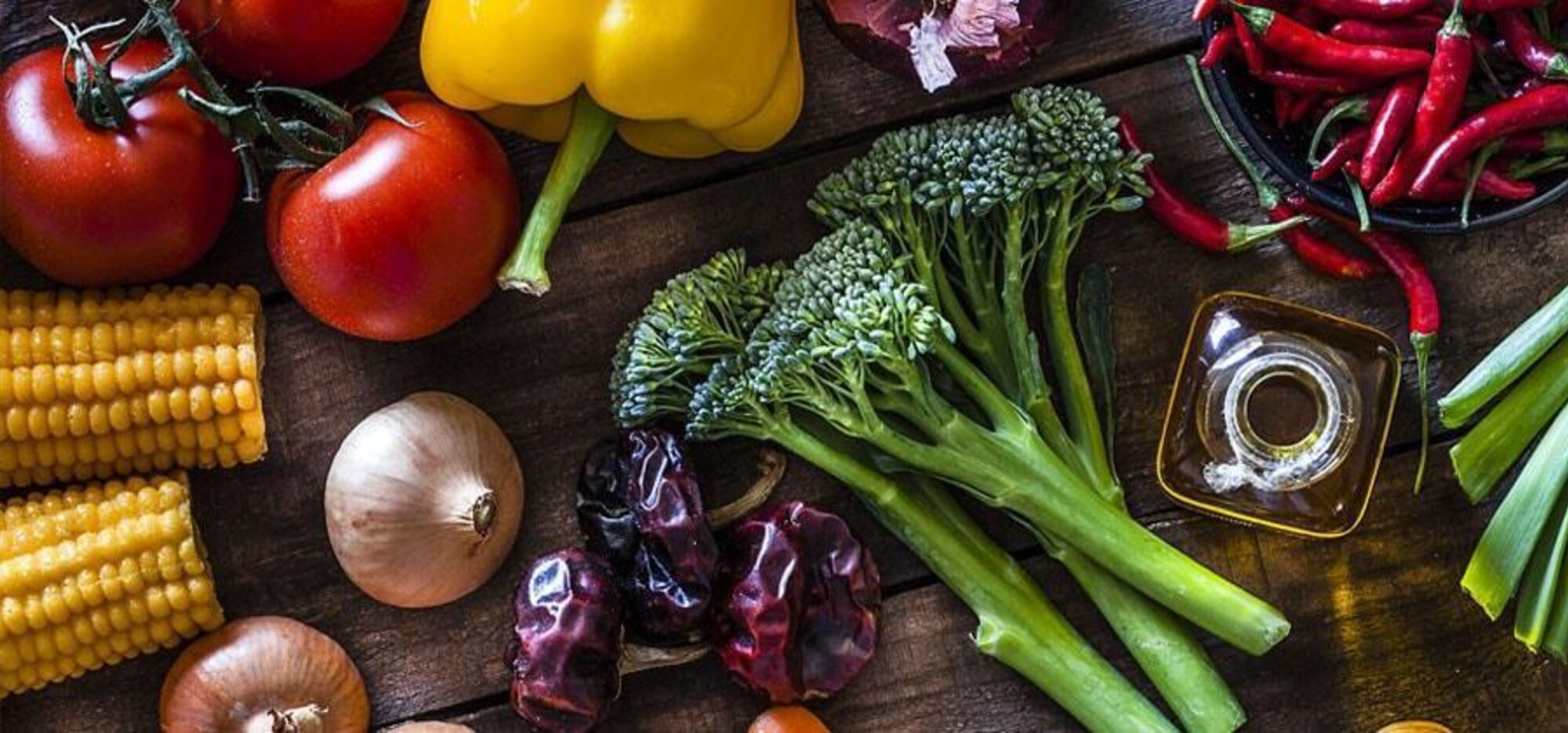 Gemüse, Chilis und Öl auf einem rustikalen Tisch
